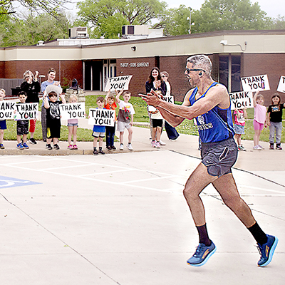 Adam Jones applauds elementary school kids cheering him on as he finishes the last leg of his triathlon to help eliminate school lunch debt.